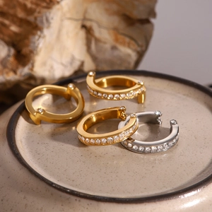 Detail of luxury gold and silver rhinestone earrings and cuffs on a ceramic tray