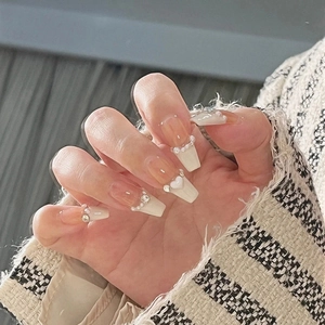 Detail view of long coffin nails with pearls, crystals, and white French tips on hand