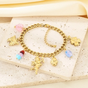 Detail of a gold charm bracelet with pink hearts and angel pendants on stone