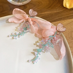 Detailed macro view of pink ribbon bow earrings with heart studs and bead tassels