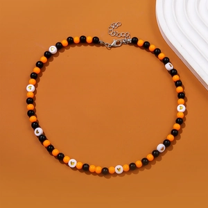 Detail of beaded necklace featuring black, orange and heart-patterned beads with clasp