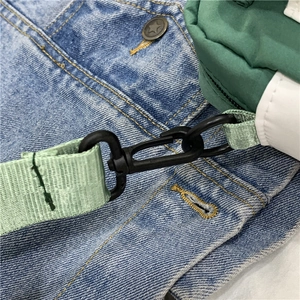 Detail of the black swivel hook connector on the green nylon strap of the crossbody bag