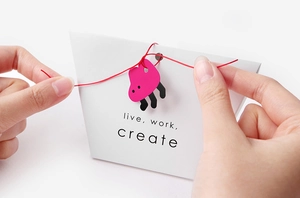 Close-up of hands opening a minimalist white paper gift bag with red string and tag