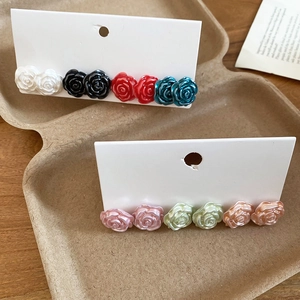 Macro view of 3D rose flower stud earrings in multiple colors on a display card