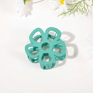 Detail view of a matte mint green flower hair claw clip with a hollow five-petal design
