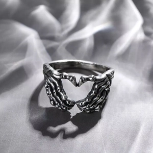 Vintage silver skull hands forming a heart shape on a grey satin background