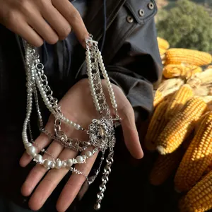 Close-up of multilayered necklace with pearls, silver chains, and carved floral pendant detail