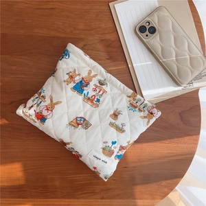 Detailed texture of white quilted makeup bag with cute rabbit and garden illustrations