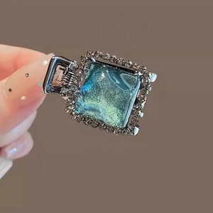 Blue marble resin hair claw clip with silver rhinestones shown in a hand-held close-up