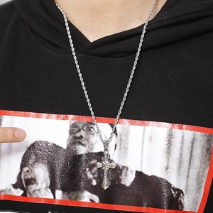 Close-up of silver steel twist chain with textured cross pendant worn on black shirt