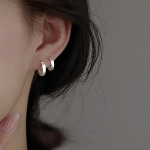 Minimalist S999 sterling silver hoop earrings with brushed matte finish on female model