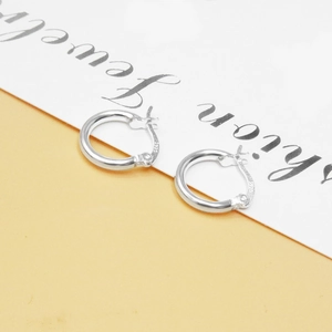 Close-up of S925 hallmark on minimalist sterling silver hoop earrings in detail view