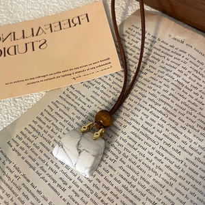 Macro shot of faux leather pendant necklace featuring white stone and vintage wooden bead