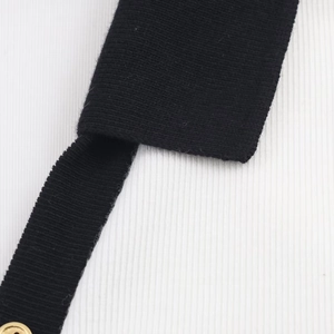 Detailed macro view of black knit fabric, white ribbed texture, and gold metal button