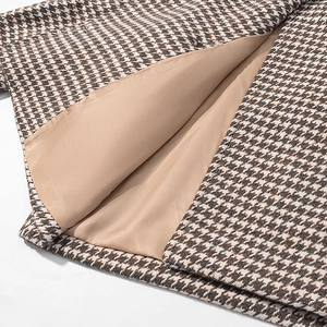Detail shot of brown houndstooth wool fabric and smooth golden polyester lining