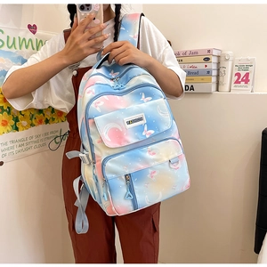 Blue and pink gradient backpack with butterfly print held by model in a study setting