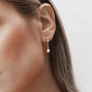 Close-up of asymmetrical S925 silver earrings with pearls and crystals on a model