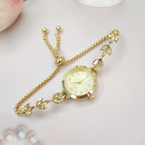 Détail d'une montre à quartz dorée avec bracelet en cristal en forme de feuille élégante