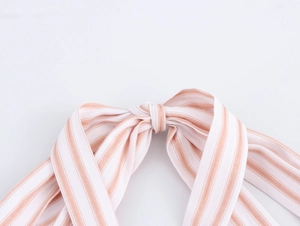 Close-up of pink and white striped fabric knot detail on a halter maxi dress