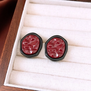 Macro shot of French vintage earrings featuring red wavy texture and black matte frame