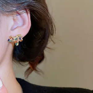 Rainbow cubic zirconia earrings in gold plating shown on a model's ear for fashion