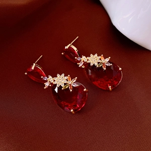 Macro shot of red pear-cut zircon teardrop earrings with golden floral accents
