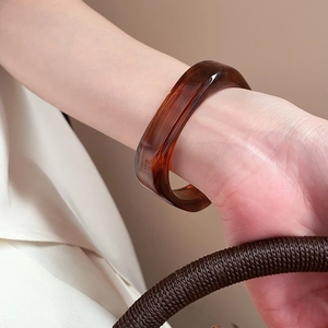Macro shot of amber resin square bangle with retro marbled texture on a model's wrist