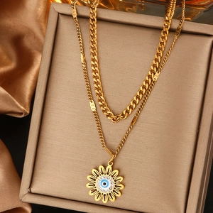 Détail d'un collier doré double épaisseur avec pendentif tournesol et design de l'œil bleu