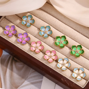 Detail of colorful flower earrings with pearls and gold plating in a wood jewelry box