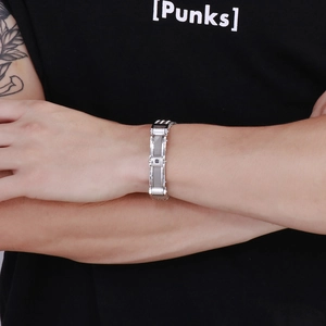 Detail of a men's stainless steel curb chain bracelet with textured inlay on a model's wrist