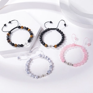 Detailed macro view of woven natural stone bracelets with silver compass charm accents