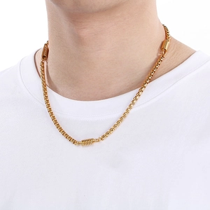 Close-up of a gold box chain necklace worn by a model on a clean white t-shirt background