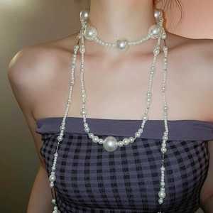 Detailed close-up of multilayer pearl necklace with varied bead sizes on a model