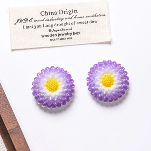 Macro detail of resin daisy flower charms with purple gradient petals and yellow core
