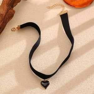 Dettaglio del girocollo in velluto nero con pendente a cuore glitterato e chiusura dorata