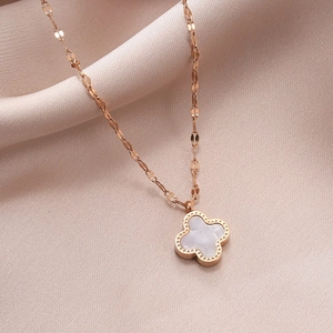 Rose gold four-leaf clover necklace with white mother of pearl inlay on silk background