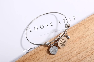 Detail of adjustable stainless steel heart bracelet with Love charm and astronaut tag