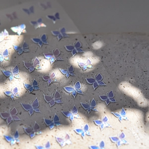Holographic laser 3D butterfly nail stickers in blue and purple on travertine stone