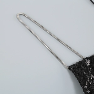 Détail de la fine bandoulière en chaîne serpent argentée sur robe noire à paillettes