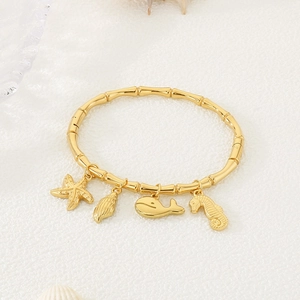 Detail of 18K gold bamboo style bangle with starfish, seashell and whale charms