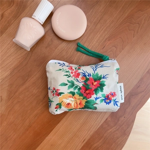 Detail of vintage floral cotton pouch showing textile texture and green cord zipper pull