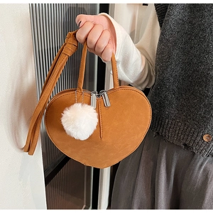 Detail der herzförmigen braunen Wildledertasche mit Doppelreißverschluss und Plüsch