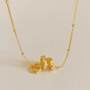 Macro detail of gold satellite chain and interlocking irregular rings with zircon stones