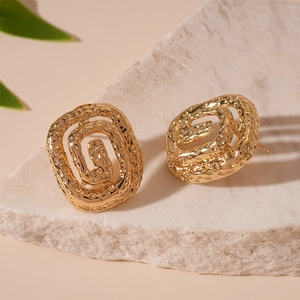 Irregular golden geometric stud earrings with hammered texture on white marble background
