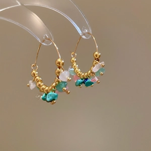 Detail of gold hoop earrings with turquoise, pink and white natural crushed stones