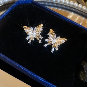 Macro view of gold butterfly stud earrings with sparkling crystals in a blue box