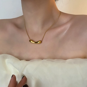 Minimalist gold snake chain necklace with irregular fluid teardrop pendant on a model