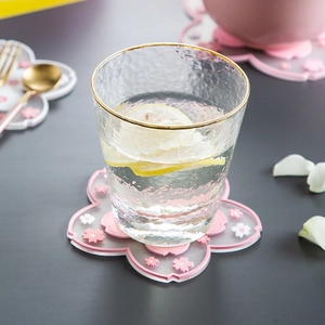 Pink cherry blossom silicone heat resistant coaster with gold rimmed glass on table