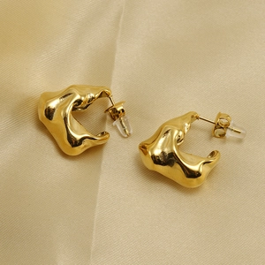 Gold plated stainless steel irregular C-shaped earrings on soft golden fabric