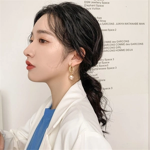 Retro golden twisted hoop earrings with white pearls worn by a model in soft light